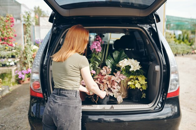 Woman placing flowers in a car compartment.